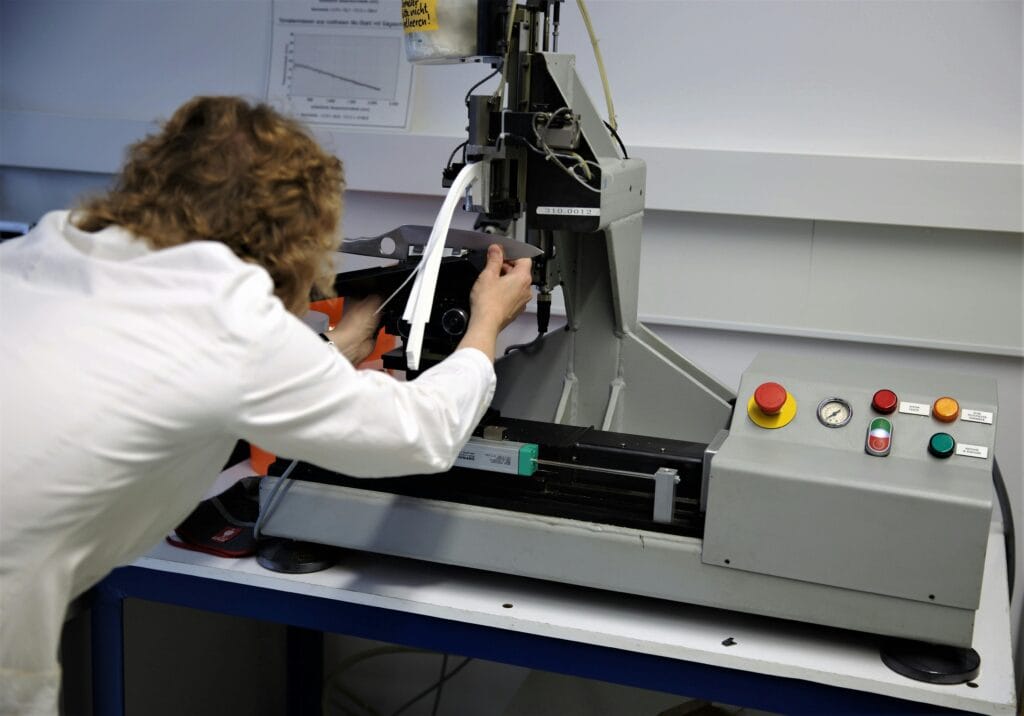 Scientist operates a precision testing machine in a modern laboratory setting.